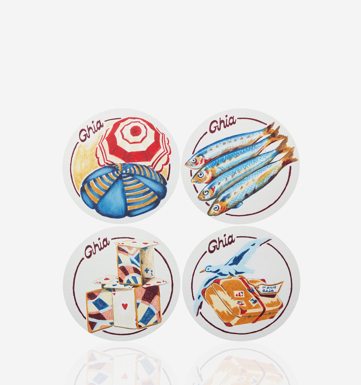 Four round Ghia coasters with illustrated designs featuring a beach umbrella, fish, stacked playing cards, and a suitcase with a bird.