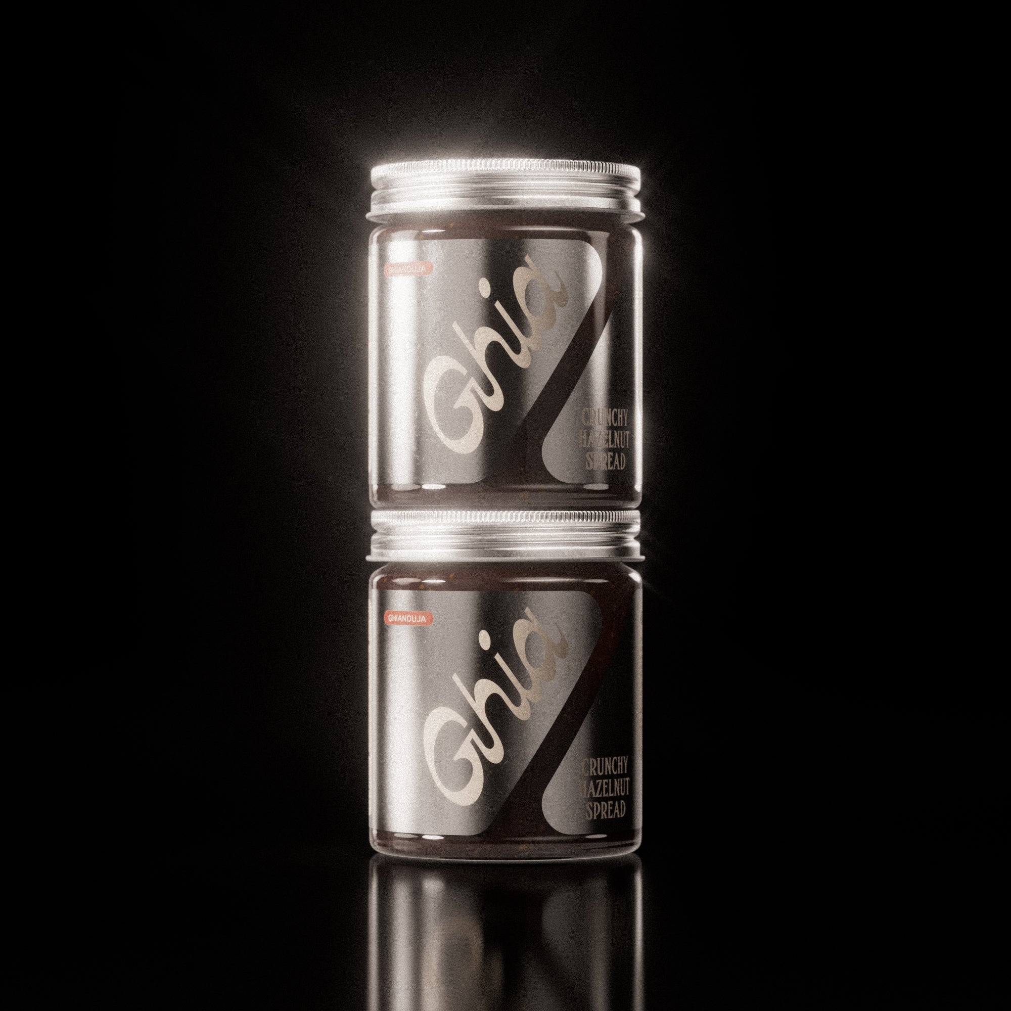 Two stacked jars of chocolate Hazelnut Spread with silver labels and bold white branding on clear glass containers.
