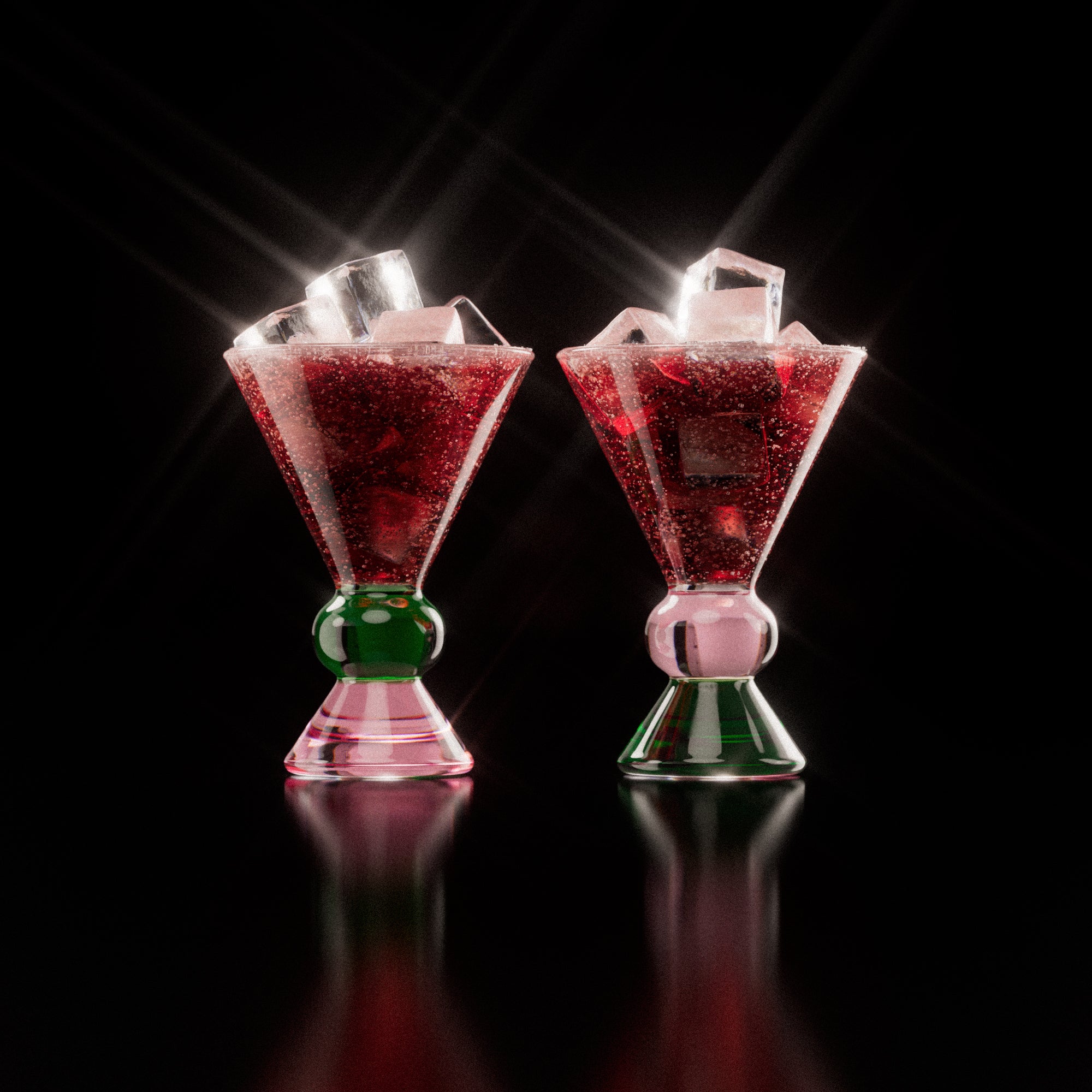 Two decorative glasses with a pink and green base, each containing a red drink with ice cubes, highlighting the distinctive totem-inspired shape of the glasses against a light background.