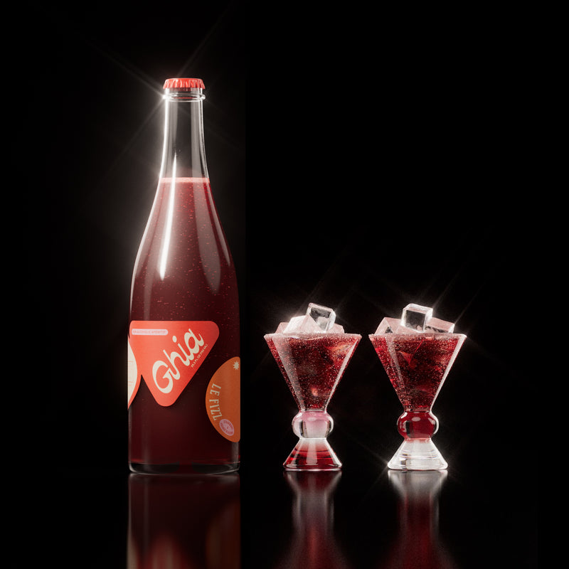 Non-alcoholic spritz in a bottle filled with a deep red strawberry and orange blossom beverage, featuring red labels. Alongside decorative cocktail glass that has a burgundy and clear base.