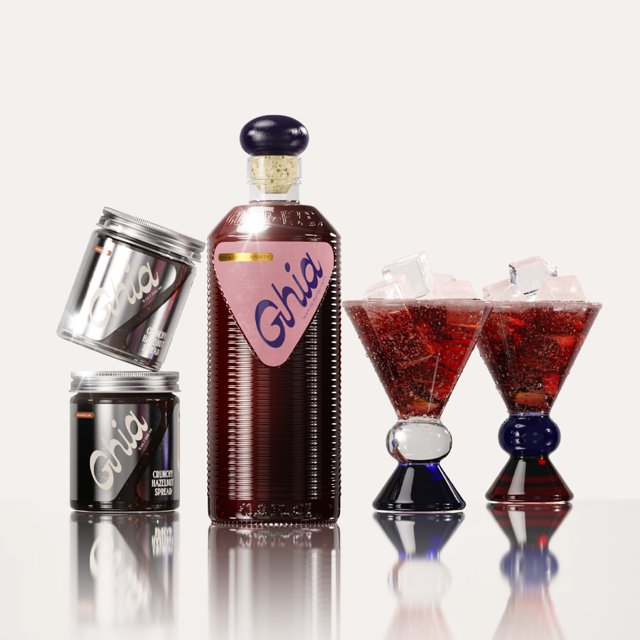 Deep-red non-alcoholic beverage in flavor Berry Apéritif in ribbed glass bottle with a pink label next to two jars of chocolate Hazelnut spread, and two cocktail glasses with a blue and amber base