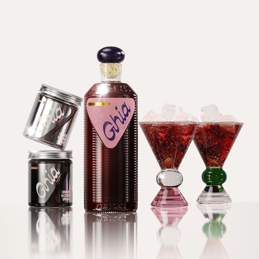 Deep-red non-alcoholic beverage in flavor Berry Apéritif in ribbed glass bottle with a pink label next to two jars of chocolate Hazelnut spread, and two cocktail glasses with a pink, clear and green base.