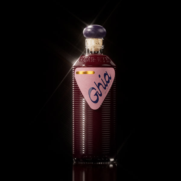 A Ghia non-alcoholic beverage in flavor Berry Apéritif clear bottle with ribbed glass, a purple cork top, and a pink label featuring bold branding on a reflective surface.