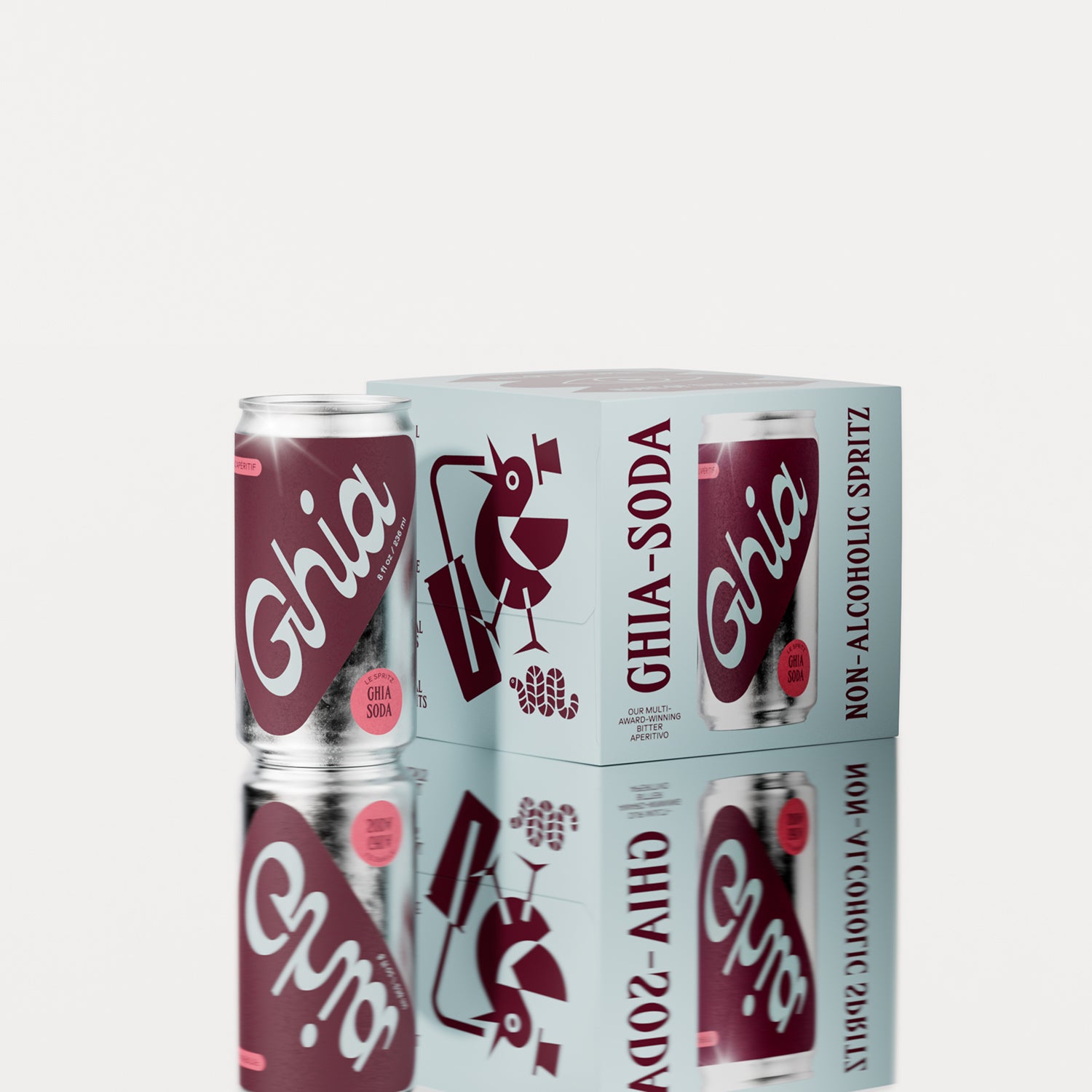 A pack of four Ghia Sumac & Chili non-alcoholic spritz cans with a burgundy box featuring illustrations. One can is placed beside the box, reflecting on a shiny surface.