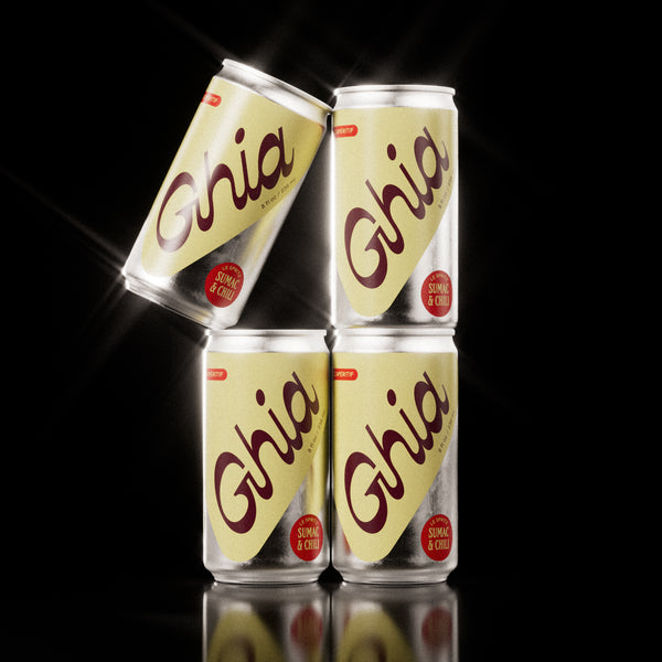 Four Ghia Sumac & Chili non-alcoholic spritz cans in a pyramid stack with bold yellow labels and red “Sumac & Chili” flavor badges, set against a black background.