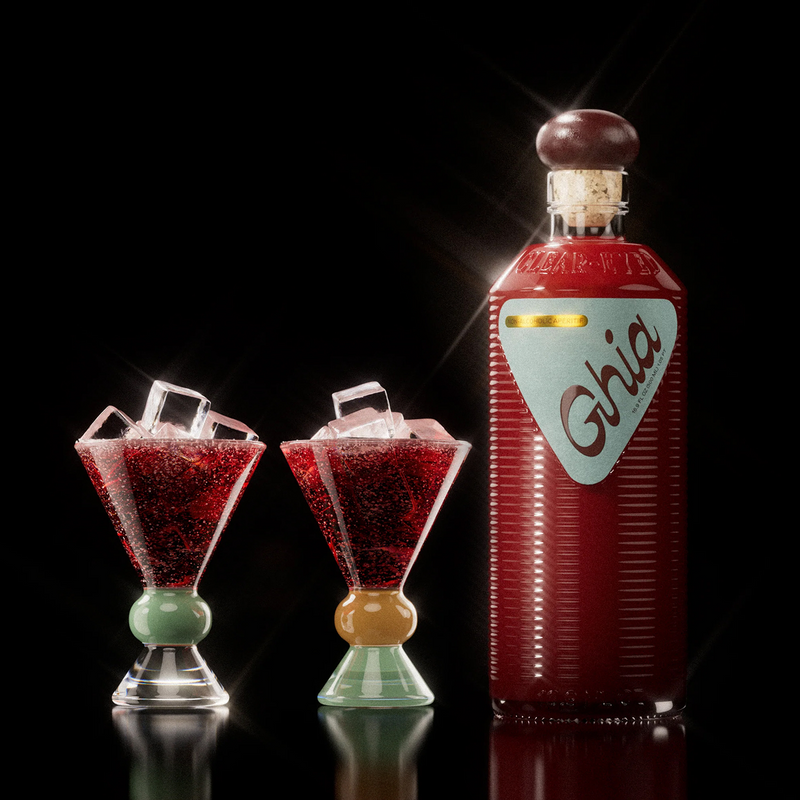 Ghia aperitif bottle beside two sculpted glasses of red spritz over ice with pink and green stems